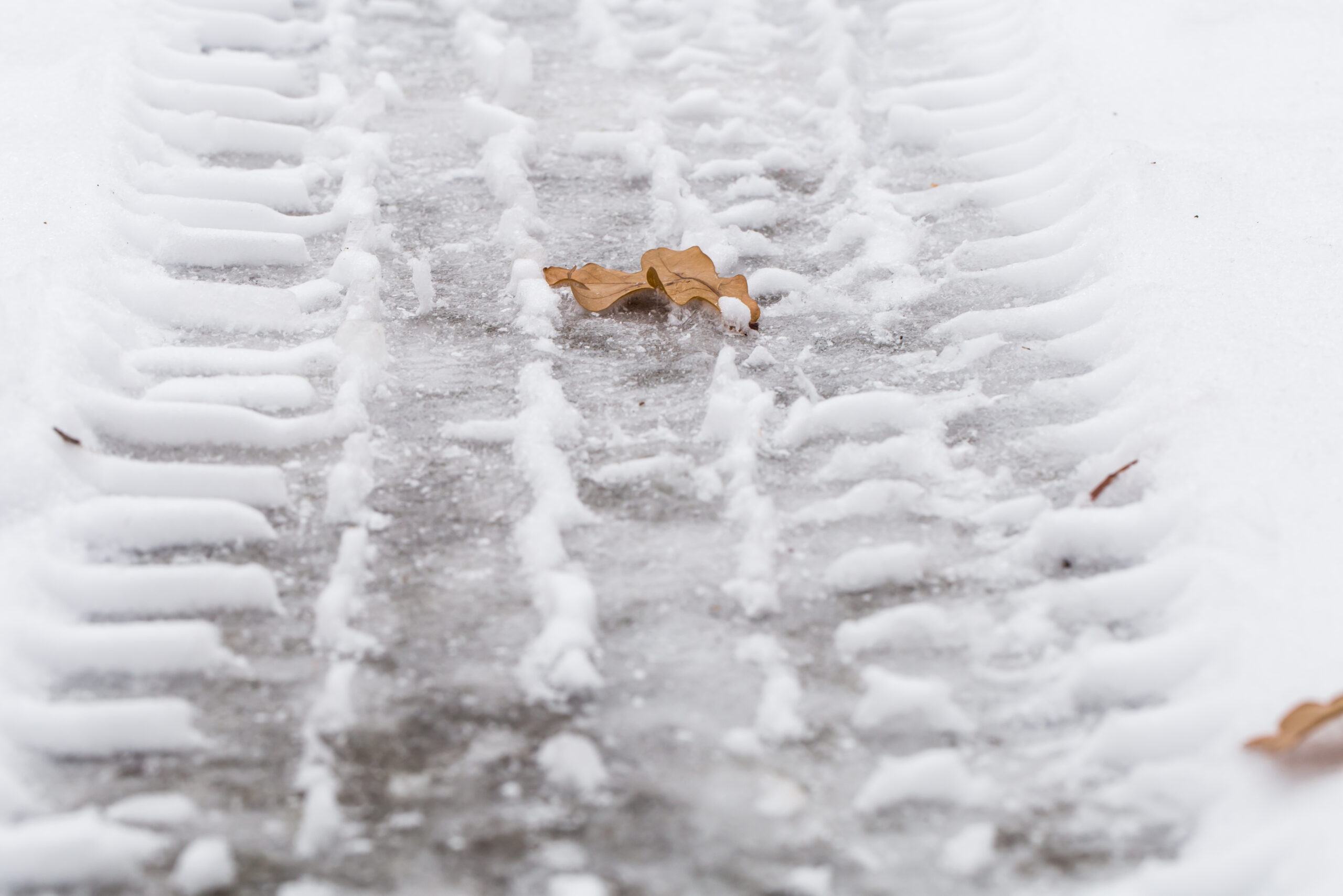 An icy sidewalk with snow and visible tracks in Lehi, Utah, representing hazardous winter conditions that can lead to slip-and-fall injuries.