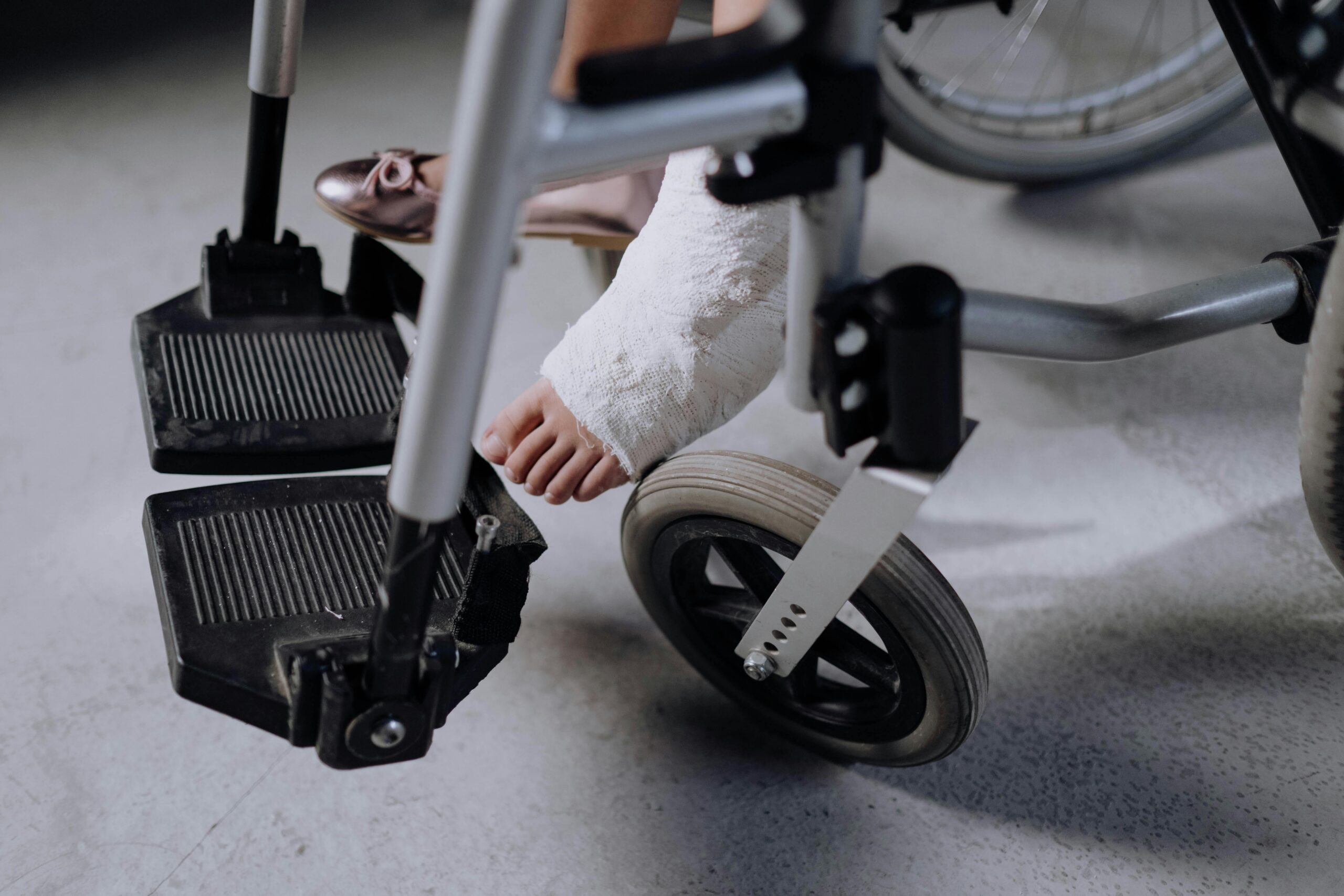 Person with a broken foot in a cast using a wheelchair during recovery after a serious accident, representing personal injury cases in Spokane.