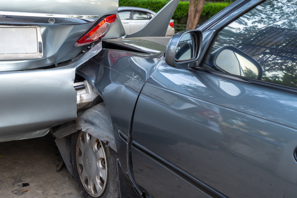 Car crash on a street involving heavily damaged vehicles and wreckage at the accident scene.