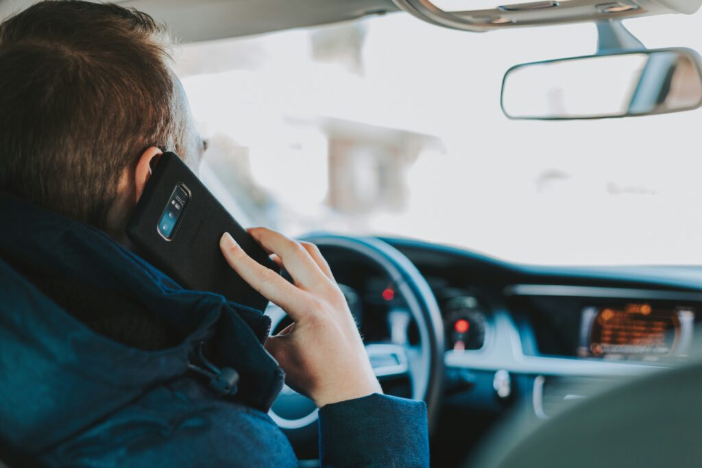 man sitting in the drivers seat holding a phone